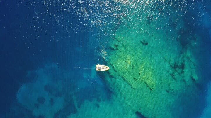 Foto Diving Chia: Drone sull'ancora. Il gommone sembra appeso a un cielo capovolto.